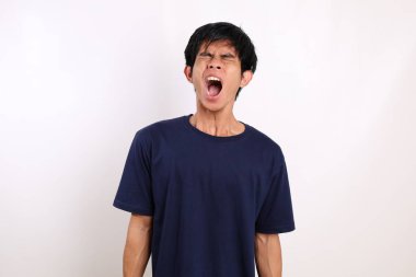 Stresli Asyalı genç adam çığlık atarken ayakta duruyor. Beyaz arkaplanda izole