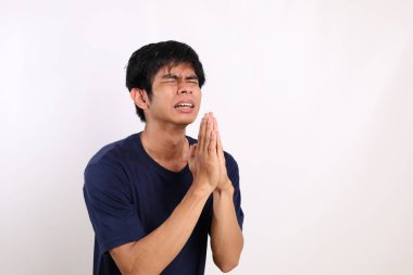 Asyalı genç bir adamın portresi. Yalvarıyor ya da jest istiyor. Beyaz arkaplanda izole
