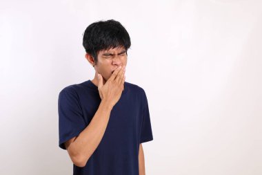 Asyalı genç adam esnerken ayakta duruyor. Kopyalama alanı ile beyaz arkaplanda izole