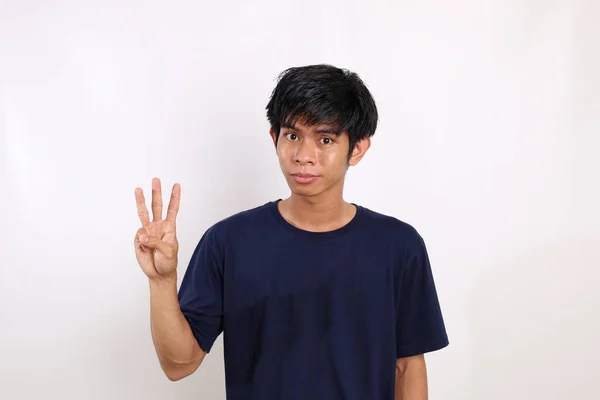 3本の指を見せながら立ち並ぶ幸せなアジア系の青年 コピースペースと白に隔離された — ストック写真