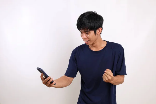 快乐的亚洲年轻人一边站着 一边用拳头从他的手机里得到好消息 与白种人隔离 — 图库照片