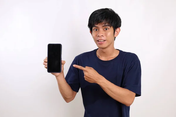 年轻的亚洲人快乐地站在那里 展示并指向空白的手机屏幕 与白种人隔离 — 图库照片