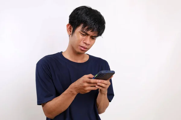 年轻的亚洲人在拿着手机打字时感到很失望 坏消息的概念 与空白隔离在白色之上 — 图库照片