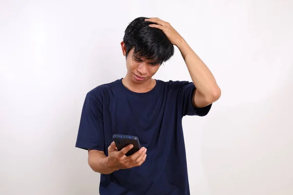 令人失望的年轻亚洲男人从他的手机里得到了坏消息 因白人背景而被隔离 — 图库照片