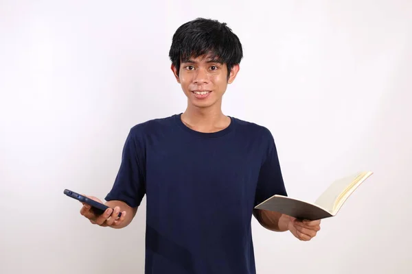 Ένας Νεαρός Ασιάτης Στέκεται Κρατώντας Ένα Βιβλίο Και Ένα Κινητό — Φωτογραφία Αρχείου