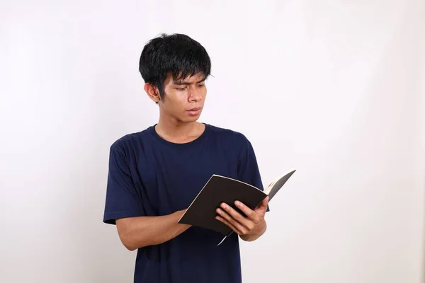 本を読みながら真面目な顔でカジュアルに若いアジア人男性の肖像画 コピースペースと白に隔離された — ストック写真