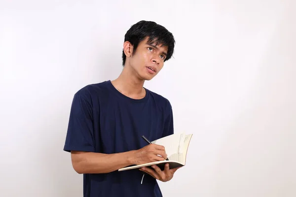 有远见的亚洲年轻人站在那里 一边写着他的书 在白色背景上与版权保护隔离 — 图库照片