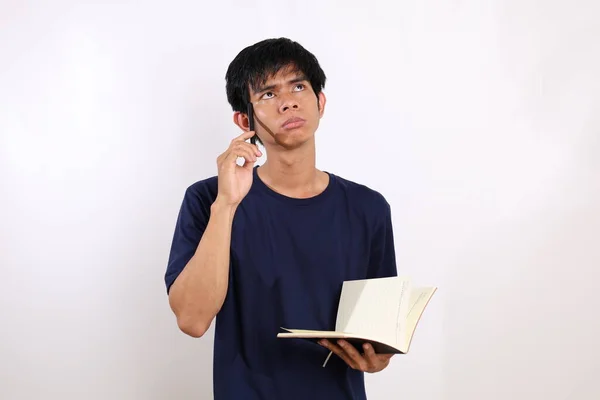 Eftertänksam Ung Asiatisk Man Som Står Och Håller Bok Isolerad — Stockfoto