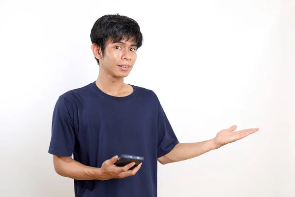 携帯電話を持ちながら立ち並んで空の空間を提示する若いアジア人男性 白に隔離された — ストック写真