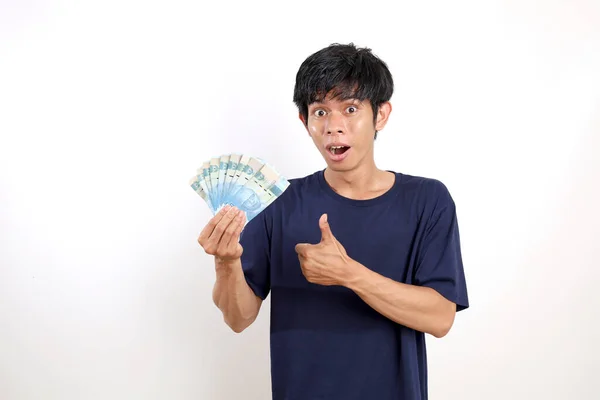 インドネシアの紙幣を持っている間 カジュアルな立ち位置に幸せな若いアジア人男性 白に隔離された — ストック写真