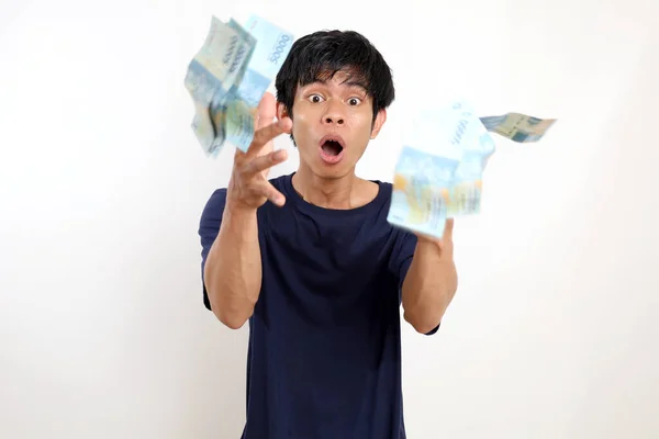 Удивленный Молодой Азиат Стоящий Разбросанными Индонезийскими Банкнотами Изолированный Белом Фоне — стоковое фото