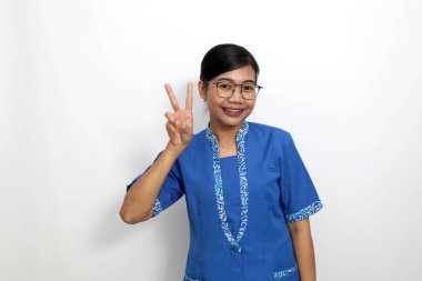 Genç Asyalı kadın iki parmağını gösterirken ayakta duruyor. Beyaz arkaplanda izole
