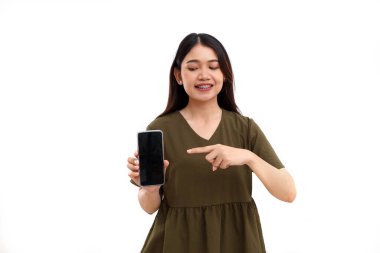 Cep telefonunun boş ekranını gösteren ya da sunan mutlu Asyalı genç bir kadın. Beyazda izole edilmiş