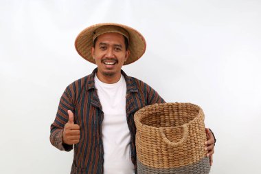 Asyalı mutlu bir çiftçi boş bir sepeti tutarken ve başparmağını kaldırırken. Beyaz arkaplanda izole