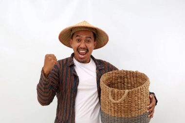 Boş bir sepeti tutarken ve elini sıkarken mutlu Asyalı çiftçi ayakta duruyor. Beyaz arkaplanda izole