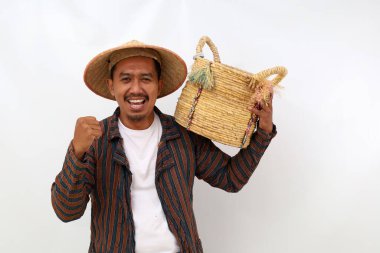 Omzunda boş bir sepeti tutarken ve elini sıkarken mutlu Asyalı çiftçi ayakta duruyor. Beyaz arkaplanda izole