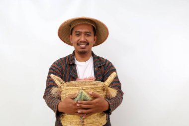 Boş bir sepeti tutarken mutlu Asyalı çiftçi ayakta duruyor. Beyaz arkaplanda izole