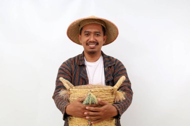 Boş bir sepeti tutarken mutlu Asyalı çiftçi ayakta duruyor. Beyaz arkaplanda izole