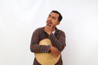 Düşünceli Asyalı çiftçi dik durup bir şeyler düşünürken. Beyaz arkaplanda izole