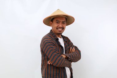 Kameraya bakarken şapkalı ve katlanmış elleri olan mutlu Asyalı çiftçi. Beyaz arkaplanda izole