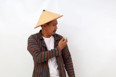 Asyalı çiftçi giysilerini temizlerken ayakta duruyor. Beyaz arkaplanda izole