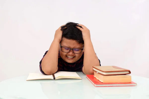 Stressed asian school boy holding his head while studying or doing his homework. Isolated on white background