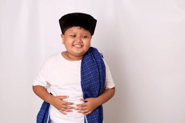 Asyalı çocuk çok fazla yemek yedikten sonra çok tok hissediyor. Çocuk karnını yiyecekle dolu tutuyor. Beyaz arkaplanda izole