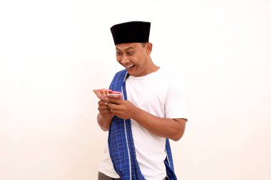 Endonezya parası elinde tutarken mutlu bir Asyalı. Beyazda izole edilmiş. Ramazan kavramı