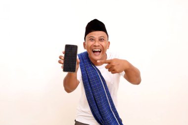 Asyalı mutlu bir adamın portresi, ayakta dururken, tutarken ve cep telefonuna işaret ederken. Beyazda izole edilmiş. Ramazan kavramı