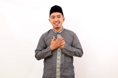 Rahatlamış Asyalı Müslüman adam göğsünü tutarken ayakta duruyor. Beyaz arkaplanda izole