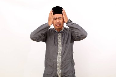 Stresli Asyalı Müslüman adam başıyla ayakta duruyor. Beyaz arkaplanda izole