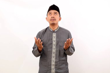 Asyalı Müslüman adam dua ediyor ve umut ediyor. Beyaz arkaplanda izole