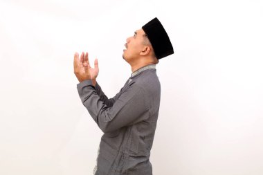 Asyalı Müslüman adamın dua eden bir el hareketiyle ayakta duruşu. Beyaz arkaplanda izole