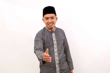 Asyalı mutlu Müslüman adam elini uzatırken ayakta duruyor. Beyaz arkaplanda izole