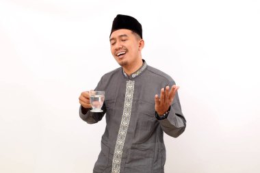 Asyalı mutlu Müslüman bir bardak su taşırken ayakta duruyor. Ramazan 'da sağlıklı bir kavram. Beyazda izole edilmiş