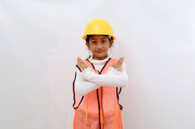 Asian little girl in the construction helmet as an engineer standing with crossed hands. Isolated on white