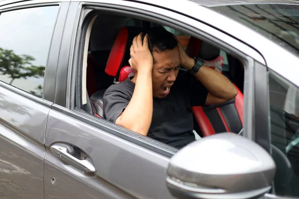 Asian man driving car while holding his head. Stressed or headache during driving concept