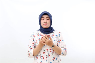 Asian veiled woman standing while praying. Isolated on white background