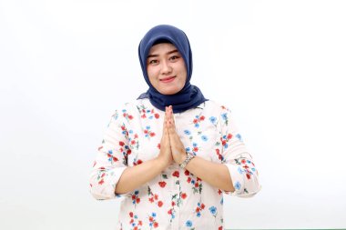 Happy asian muslim woman standing while showing greeting or welcoming hand gesture.