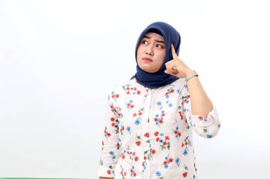 Thoughtful asian muslim woman standing while imaging and looking up. Isolated on white background