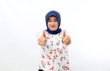Happy asian muslim woman standing while showing thumbs up. Isolated on white background