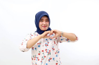 Happy asian muslim woman standing while showing love or heart shape with her hands
