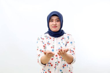 Happy asian muslim woman standing while holding and presenting something. Isolated on white