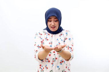 Surprised asian muslim woman standing while holding and presenting something. Isolated on white