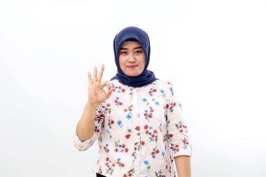 Happy asian muslim woman standing while showing okay hand gesture. Isolated on white background