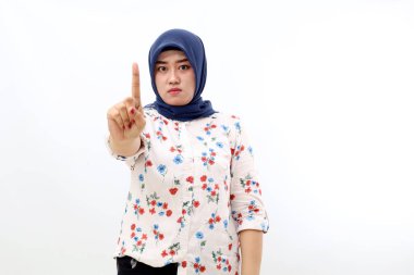 Asian muslim woman standing while showing attention with her finger. Isolated on white background