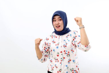 Excited asian muslim woman standing with clenched hands. Isolated on white background
