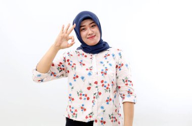 Happy asian muslim woman standing while showing okay hand gesture. Isolated on white background