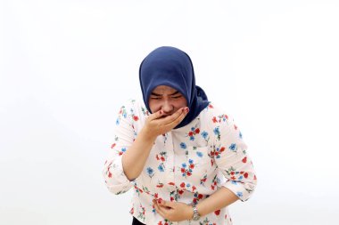 Asian muslim woman standing while holding her stomach and feeling nauseous and going to vomit