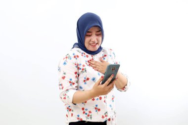 Happy asian muslim woman standing while holding a cell phone. Isolated on white background